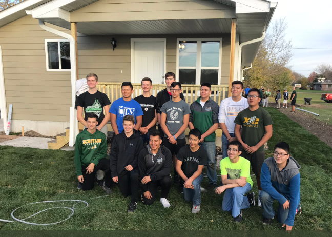 The SCHS boys basketball team posing in front of a house they helped build.