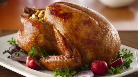 A golden brown turkey sits on a plate. 