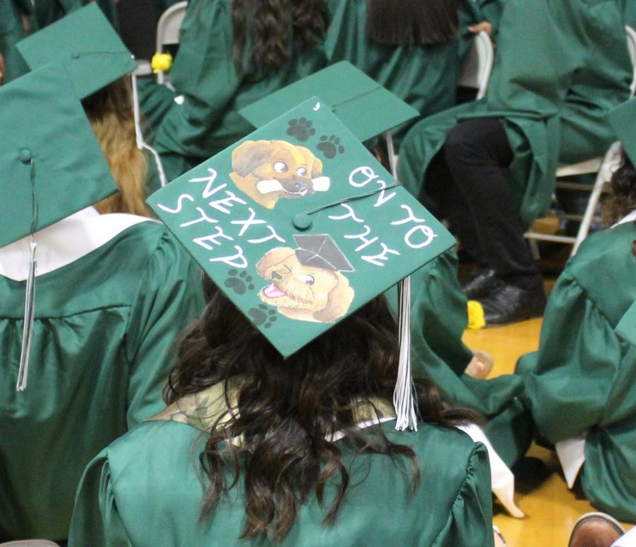 A Graduating Senior wears her cap with a design reading On to the next step. 
