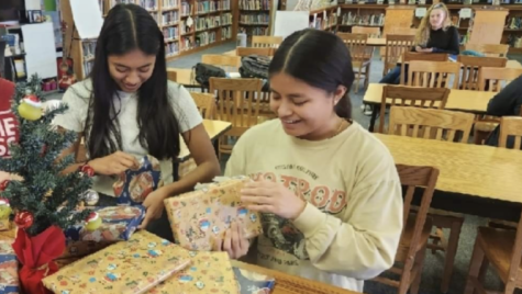 Seniors, Niurka Castro and Kathryn Tzunux unwrapping their gifts in the library. 