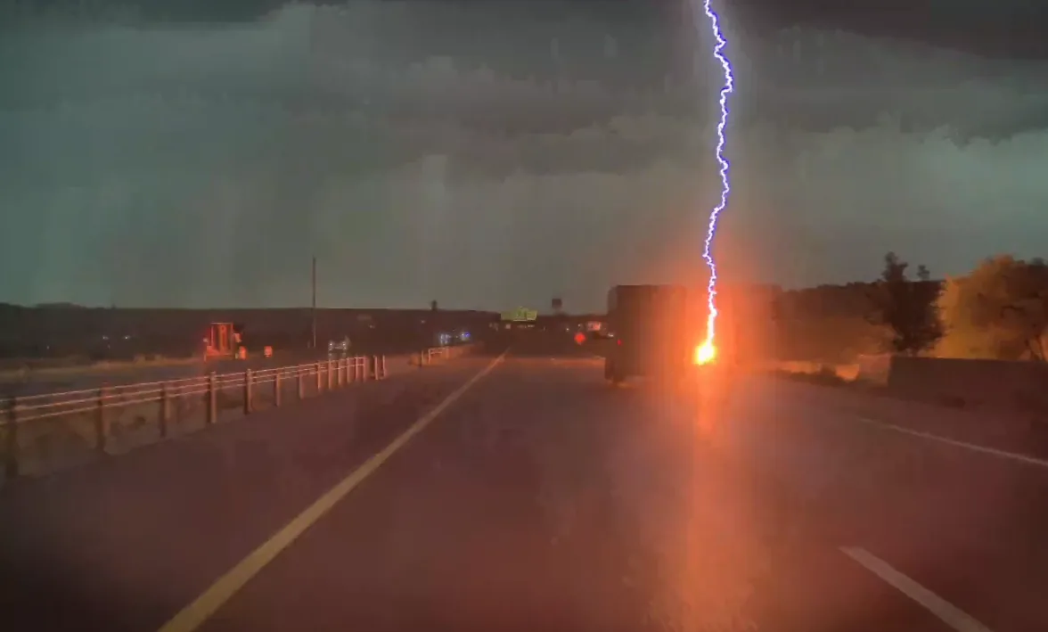 Lightning strikes near a highway shoulder as a truck drives past in northern Utah